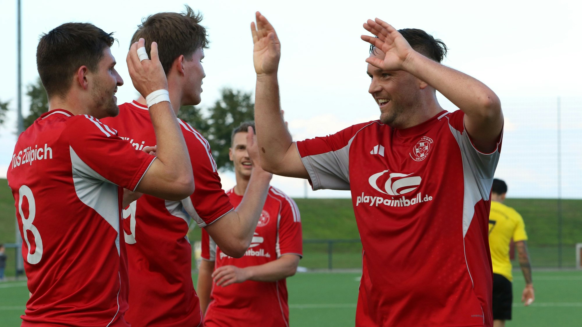 Das Bild zeigt drei Fußballer, die sich nach einem Tor freuen.