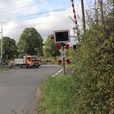 Das Bild zeigt einen Bahnübergang im Grünen.