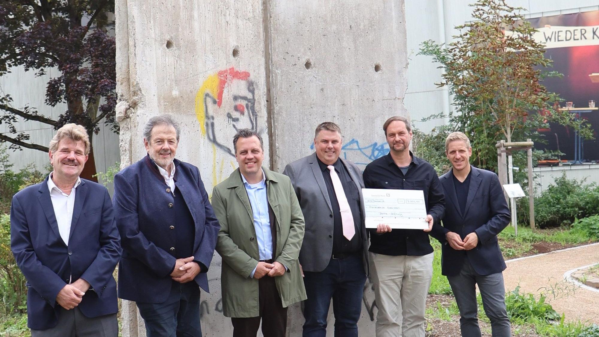 Politiker und der Schuldirektor der Marienschule Euskirchen Michael Mombaur stehen vor Originalelementen der Berliner Mauer.