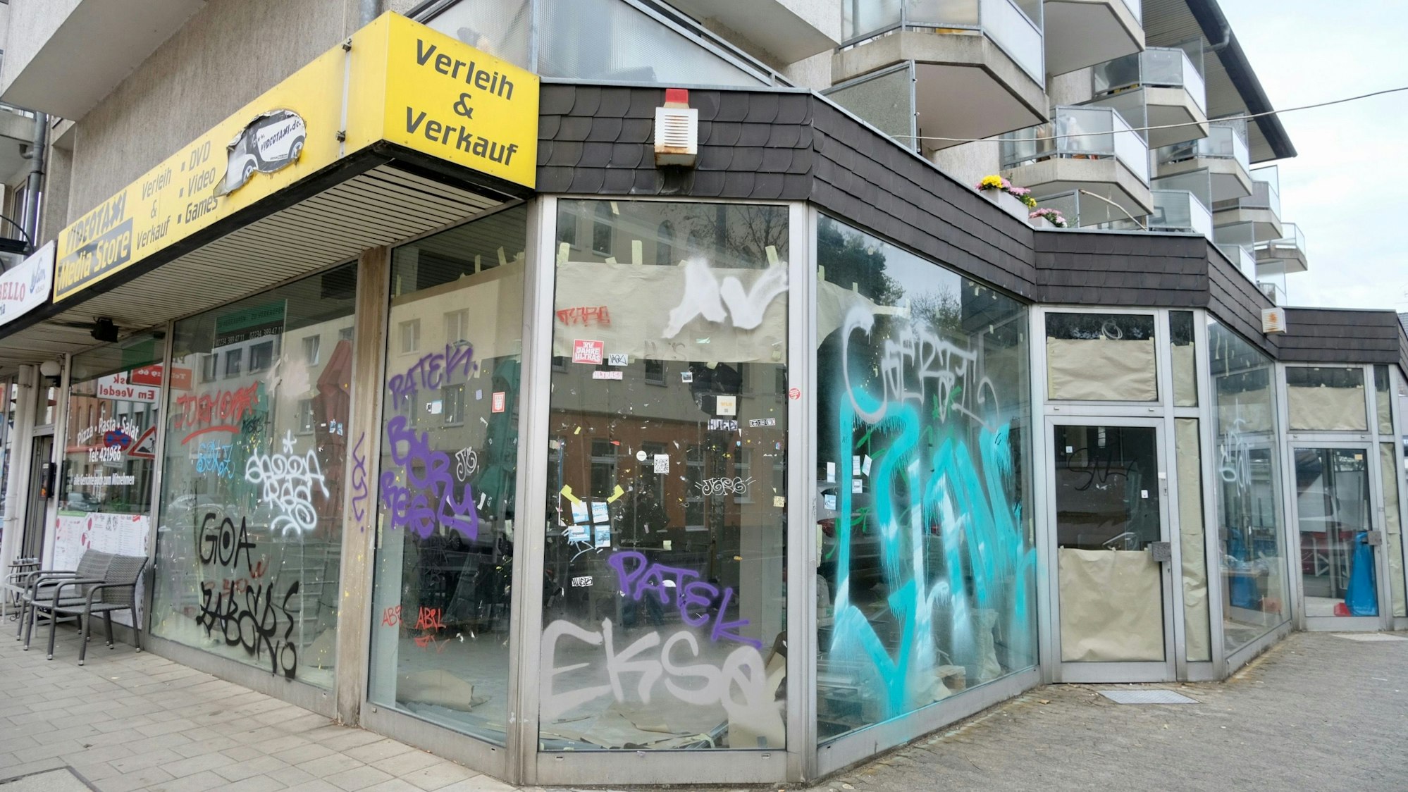 Bodentiefe Fenster eines leerstehenden Eck-Ladenlokals sind besprüht. Das ganze Ensemble bietet einen erbärmlichen Anblick.