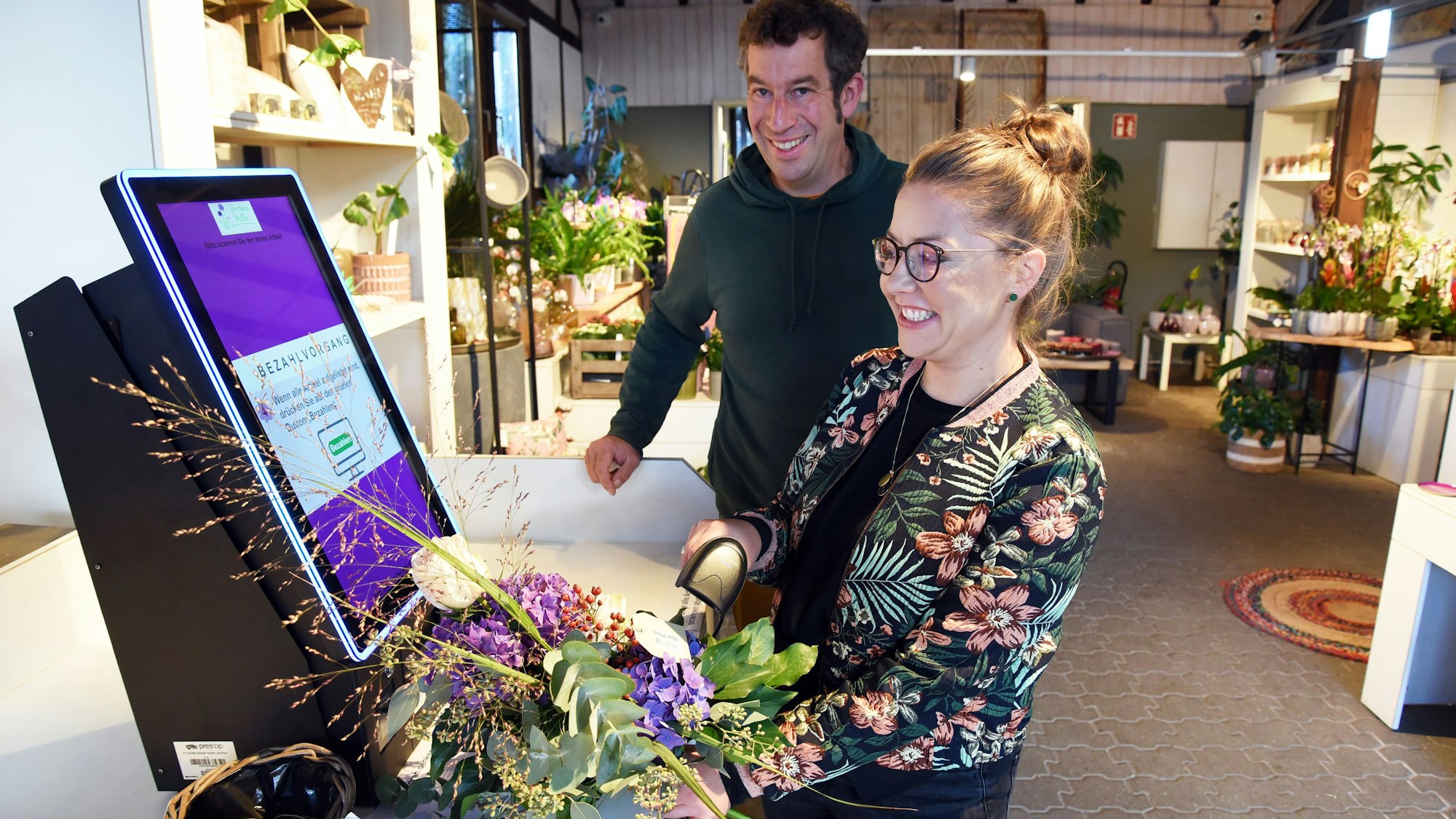 Das Foto zeigt die Inhaber der Gärtnerei am Selbstbedienungs-Terminal.
