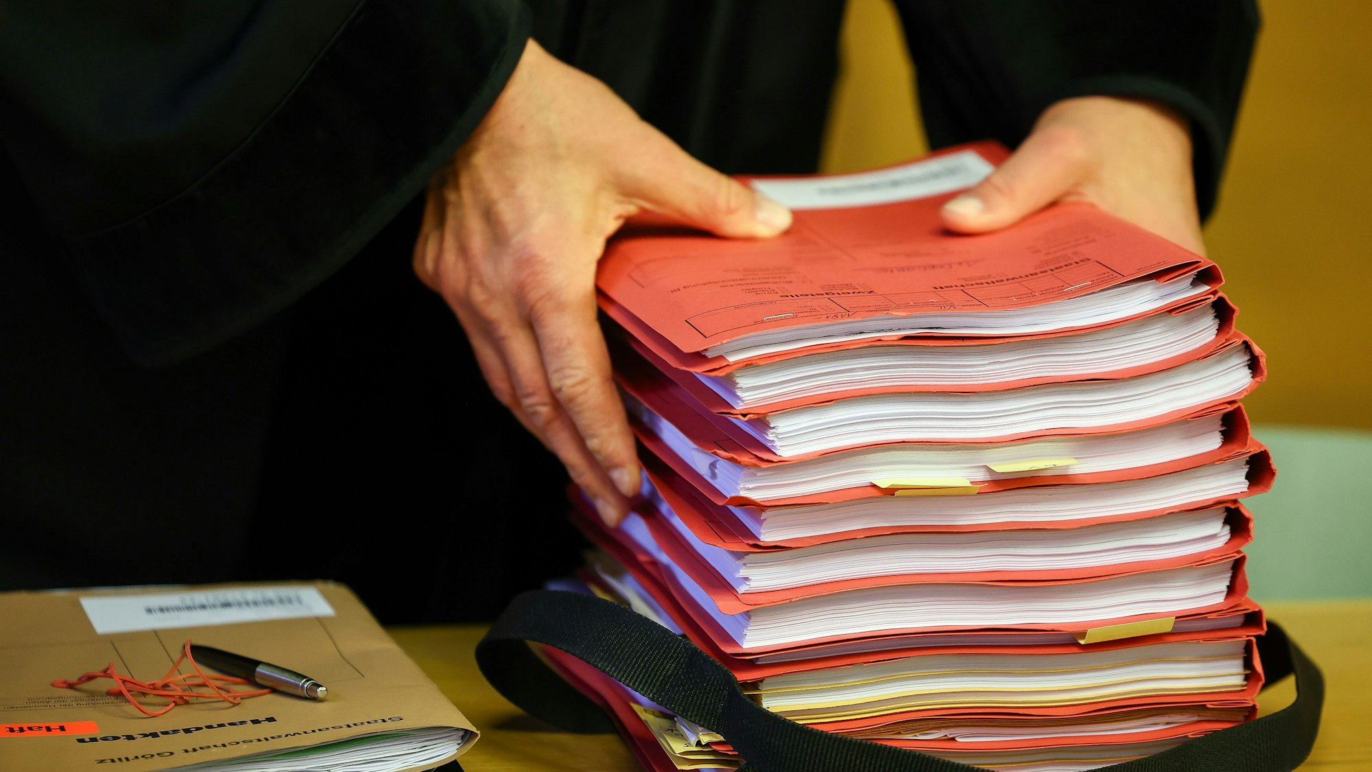 Ein Staatsanwalt legt einen Stapel Akten vor Prozessbeginn auf seinen Tisch im Gericht.