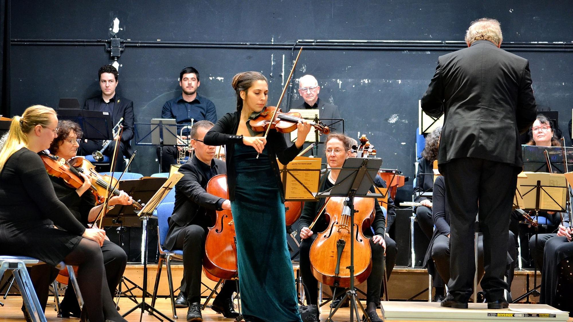 Das Bild zeigt Musikerinnen, Musiker und den Dirigenten auf der Bühne.
