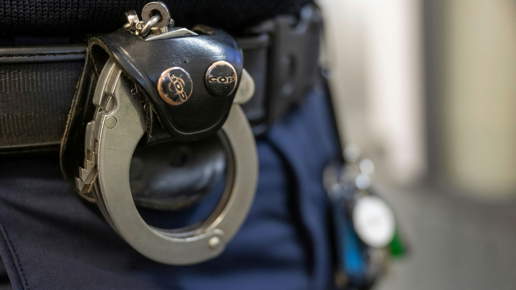 Eine Handschelle hängt am Gürtel eines Polizisten. (Symbolbild)