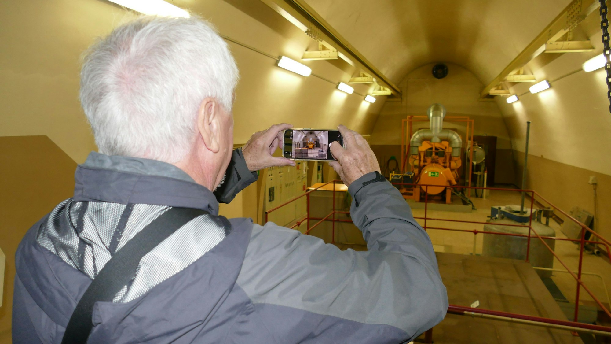 Ein Mann fotografiert mit seinem Handy in einem tunnelartigen Gewölbe.