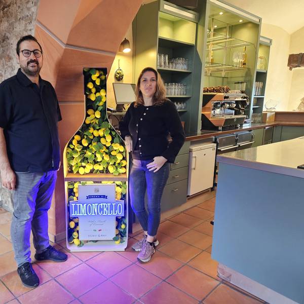 Melih Aydogdu und seine Frau Özgül stehen neben einer großen Werbung für Limoncello.