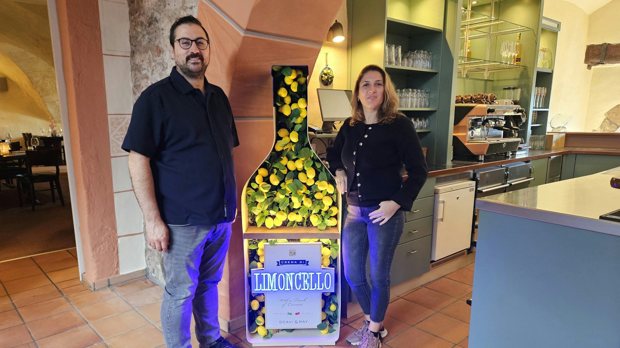 Melih Aydogdu und seine Frau Özgül stehen neben einer großen Werbung für Limoncello.