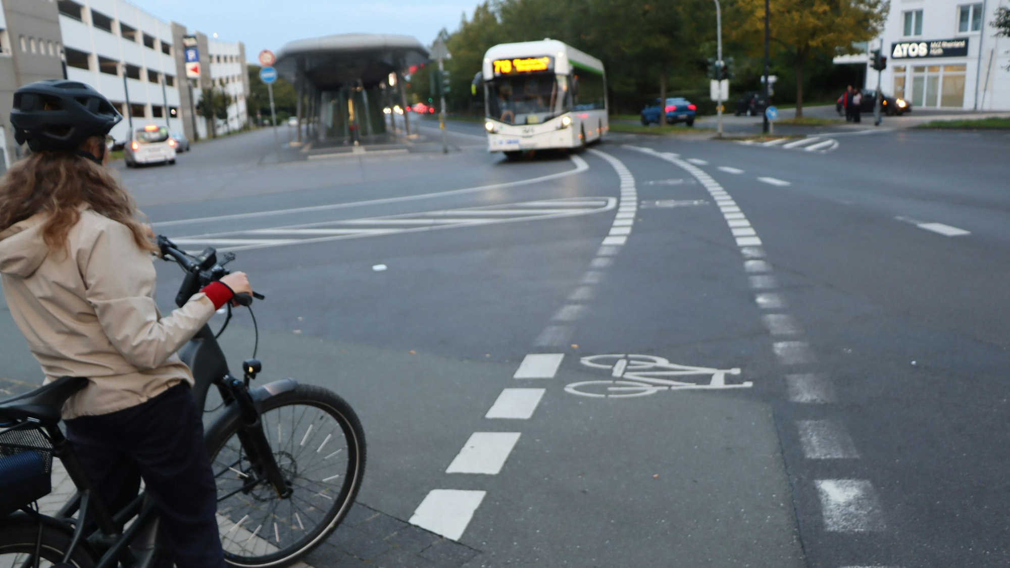 Das Foto zeigt eine Radfahrerin auf dem Radweg am Busbahnhof, der gerade von einem Bus gekreuzt wird.