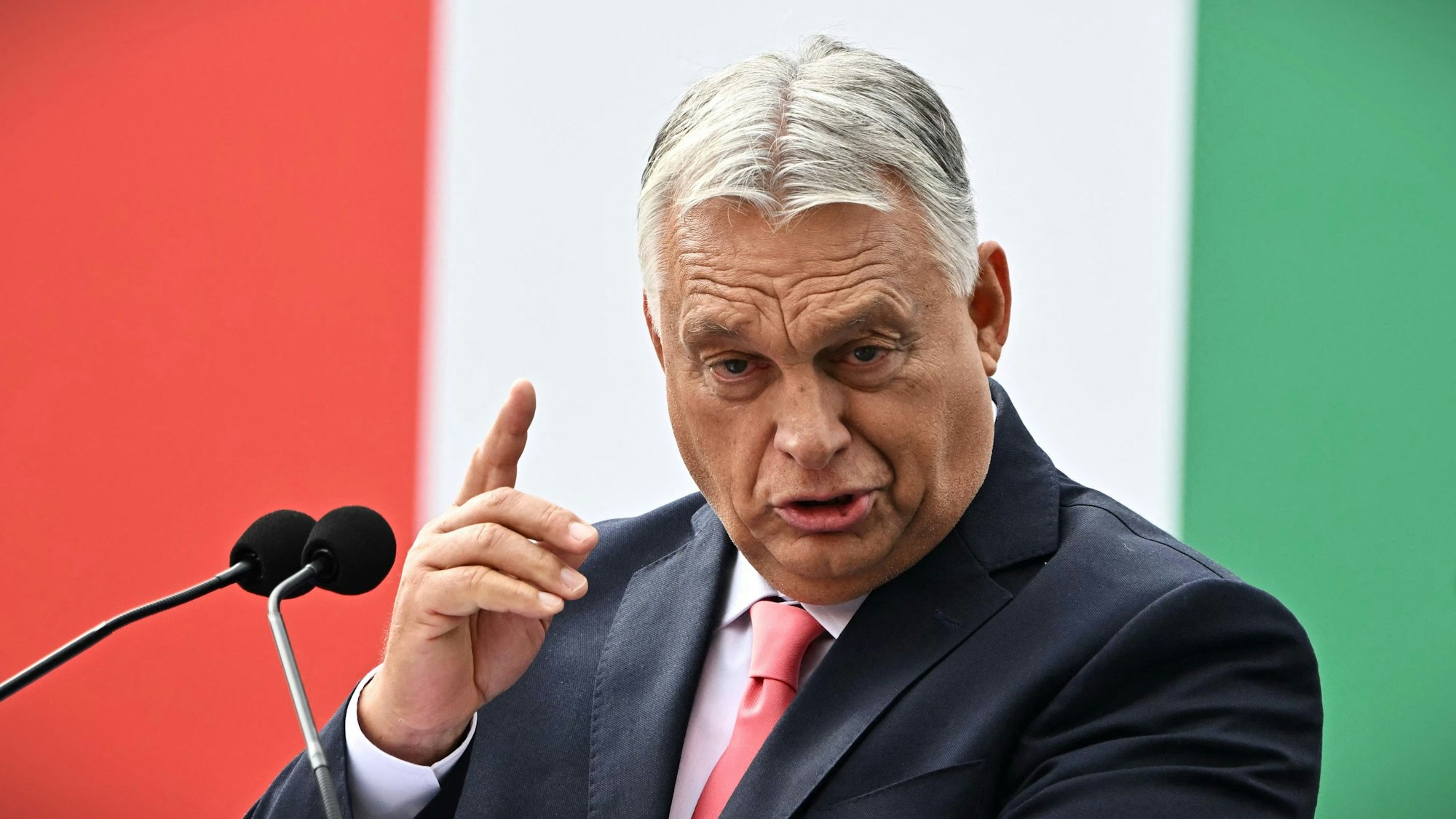 Der ungarische Ministerpräsident Viktor Orbán steht vor einer Fahne seines Landes und hält eine Rede.