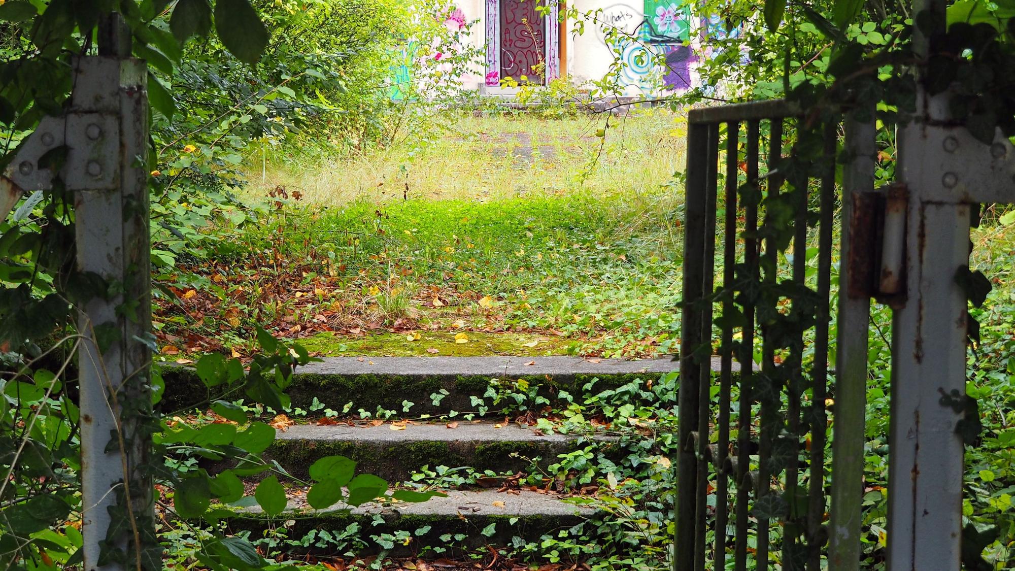 Treppen führen zu einem Vorplatz vor einem leerstehenden Gebäude.