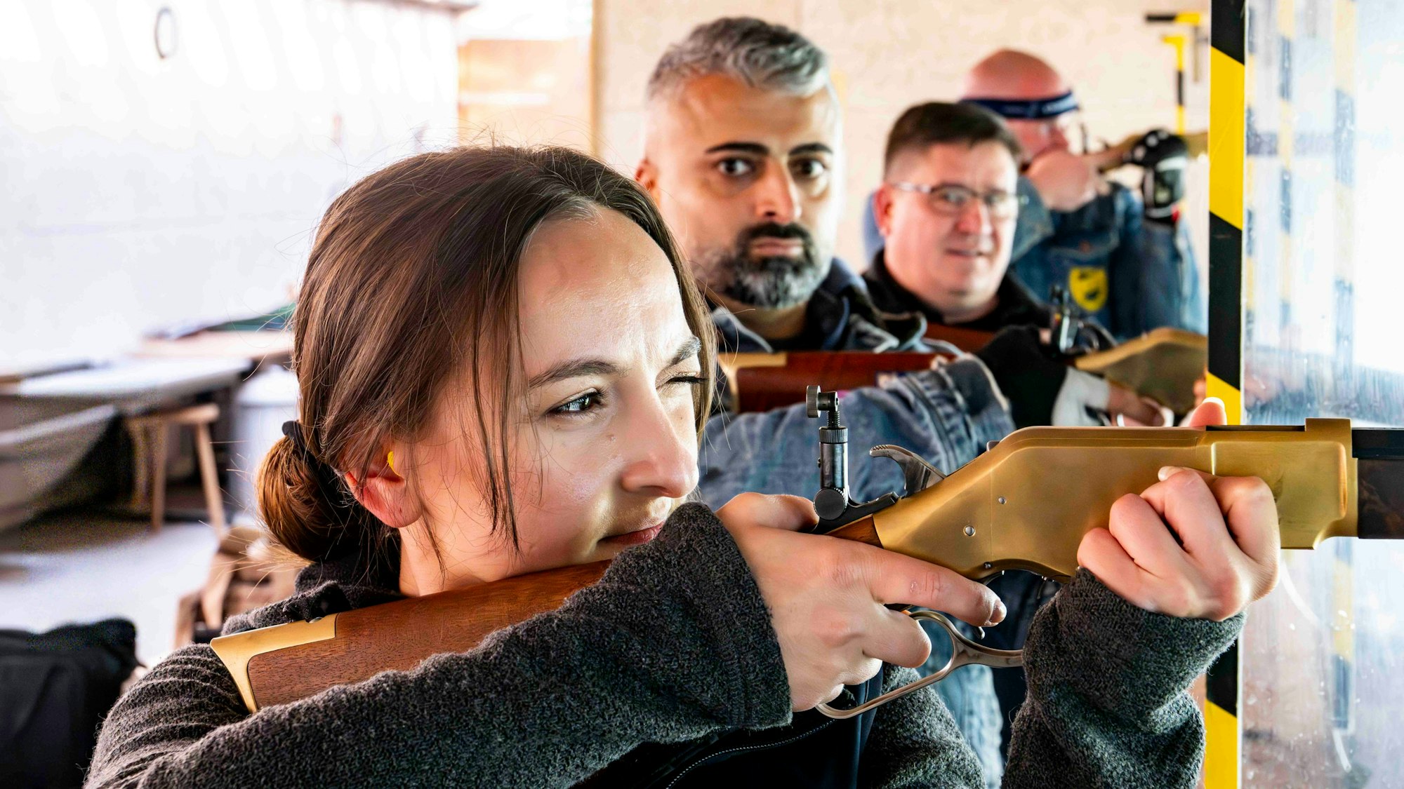 Elena Kapp hat ein Auge geschlossen und schaut konzentriert durch die Zielvorrichtung an einem Gewehr.