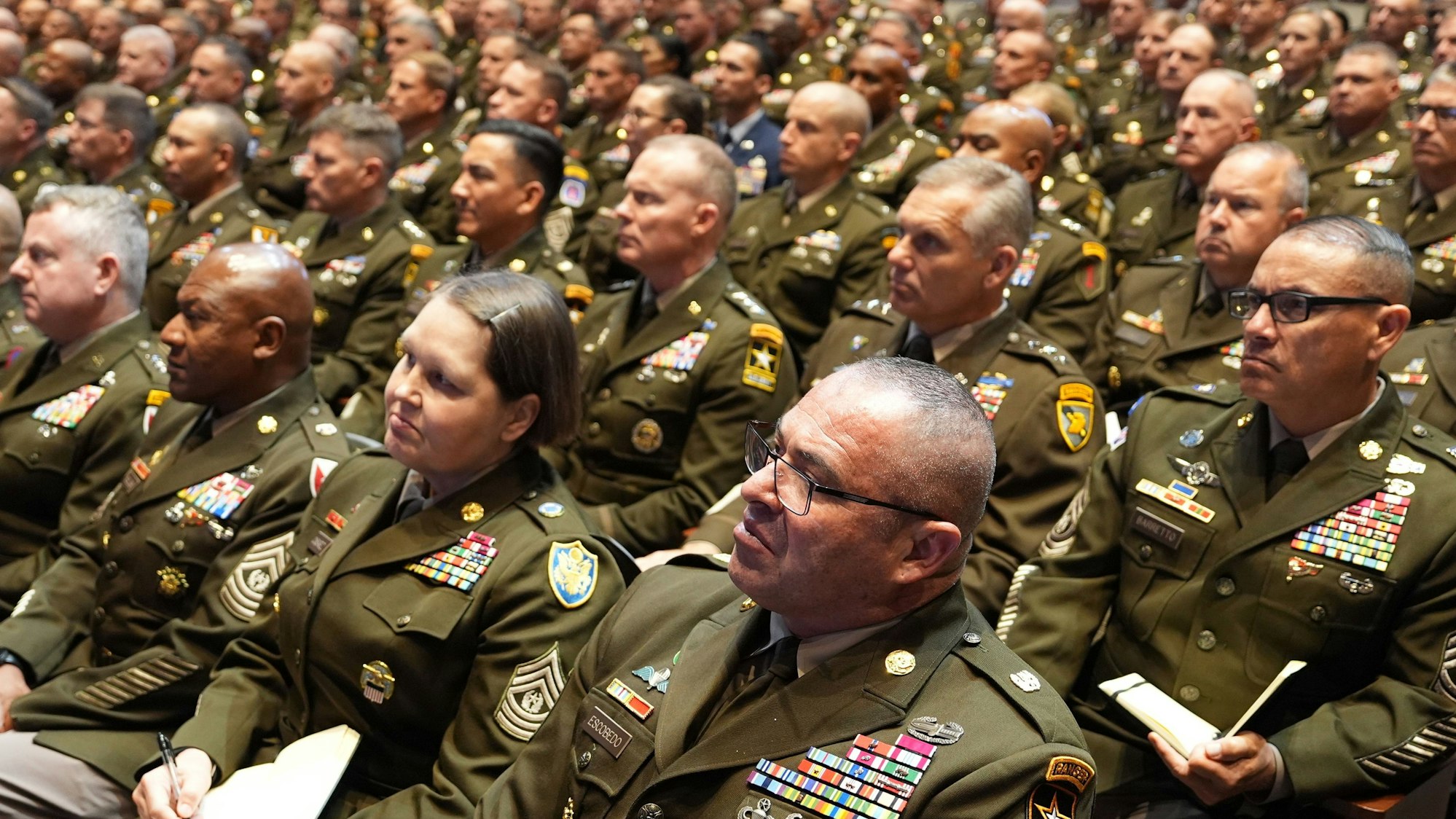 Hochrangige Führungskräfte des US-Militärs hören US-Präsident Donald Trump mit versteinerter Miene zu, als er in der Marine Corps Base Quantico spricht.