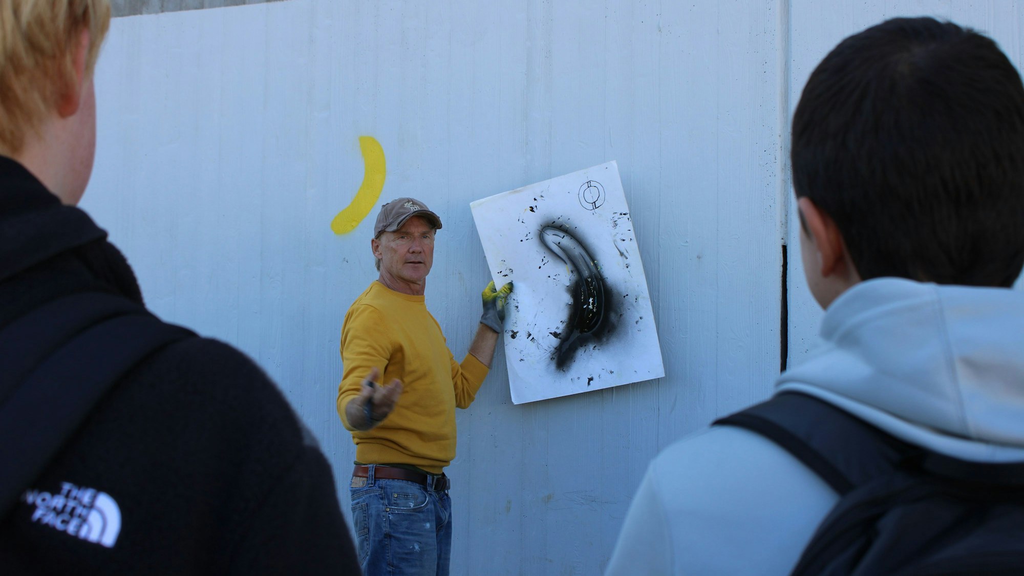 Thomas Baumgärtel zeigt den Jugendlichen, wie er seine bekannte Banane mit zwei Schablonen sprayt.