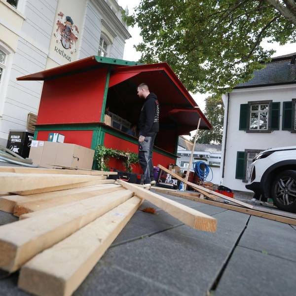 Holzlatten liegen vor einer rot-grünen Bude, die gerade aufgebaut wird.