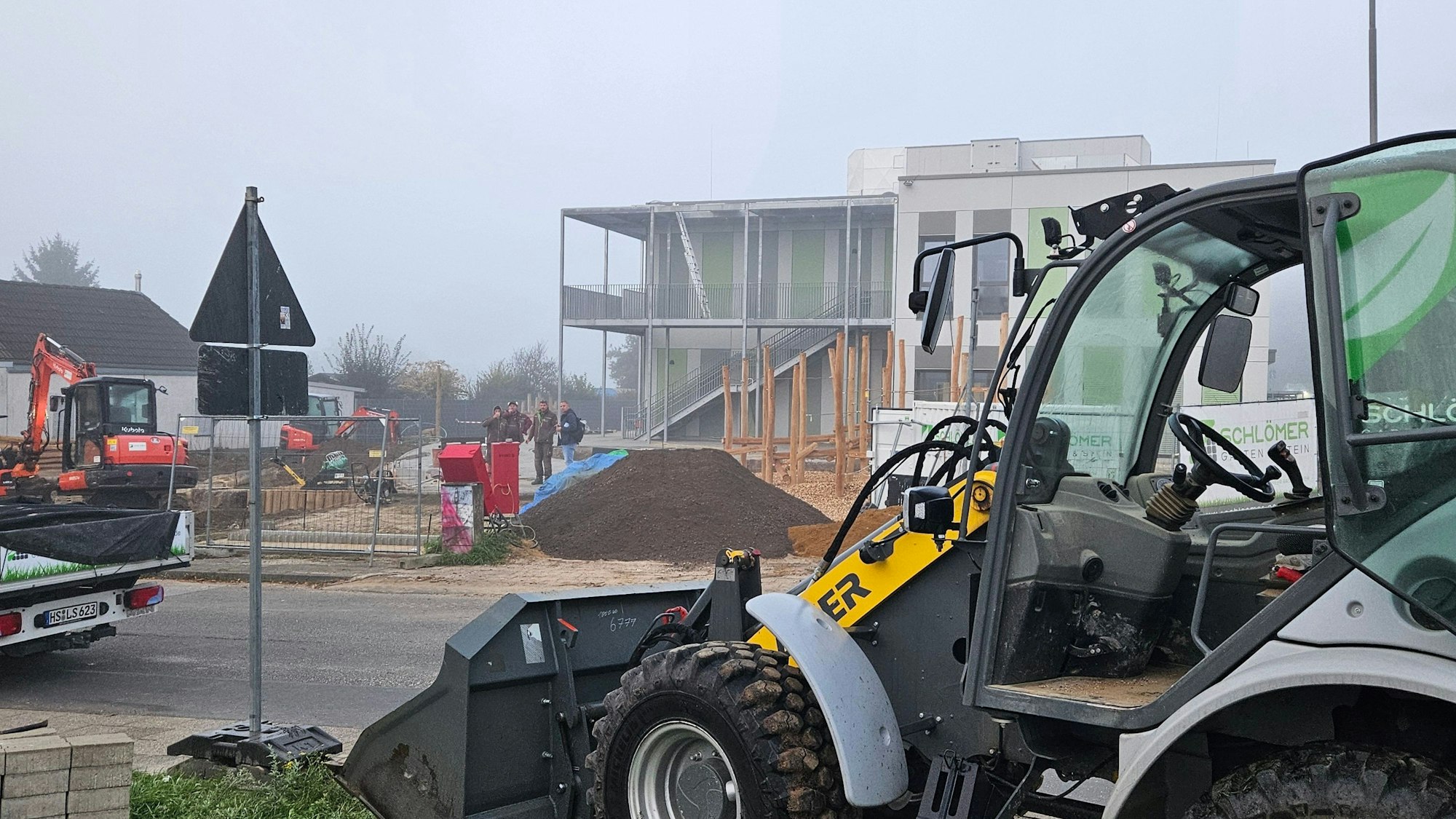 Zu sehen ist die Baustelle für einen Kindergarten mit einem Radlader und einem kleinen Bagger.