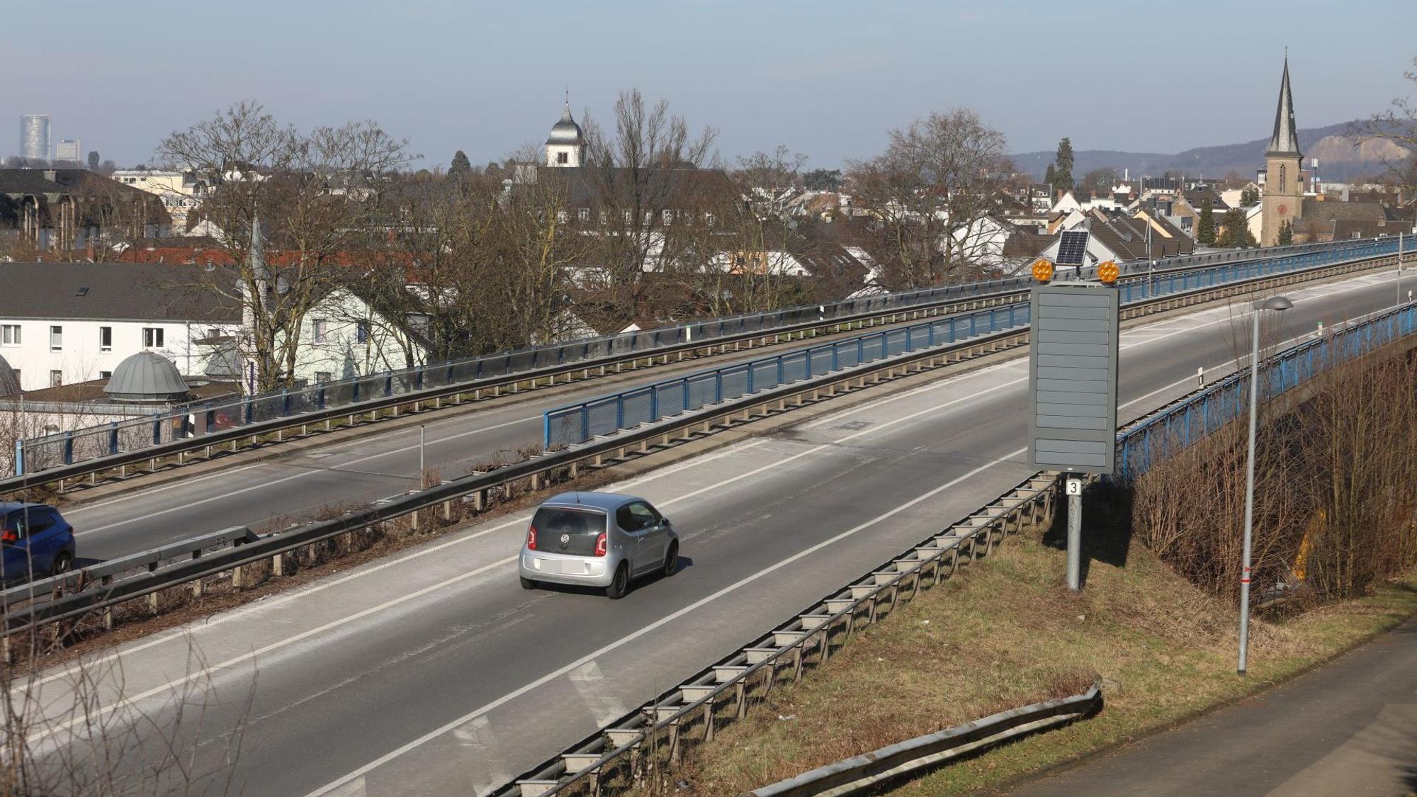 Autos fahren über eine Brücke, im Hintergrund die Altstadt von Königswinter.