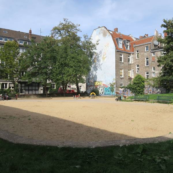 Eine große Sandfläche wird von Rasenflächen eingefasst.
