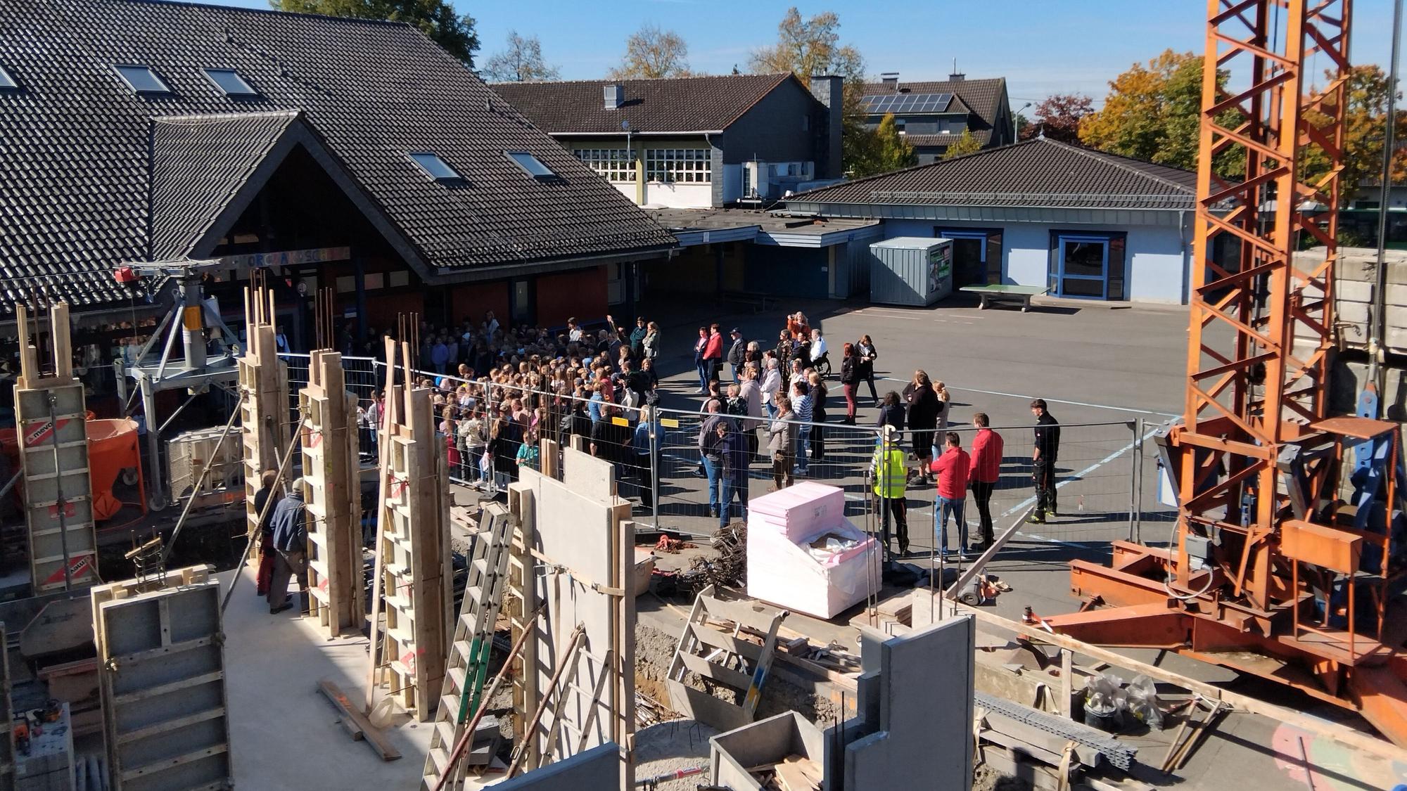 Beim Richtfest der Grundschule Much-Marienfeld sangen die Kinder ein Lied. Das erste Gebäude steht im Rohbau, das zweite wächst auf dem Schulhof.