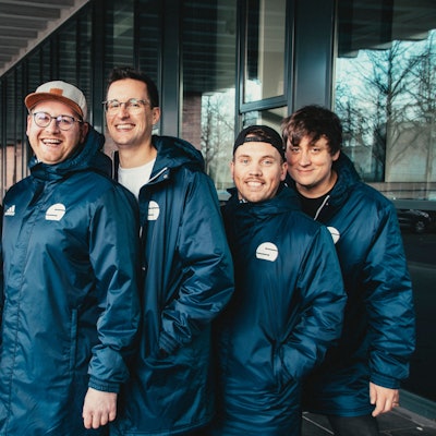 Fünf junge Männer in gleichen Windjacken.