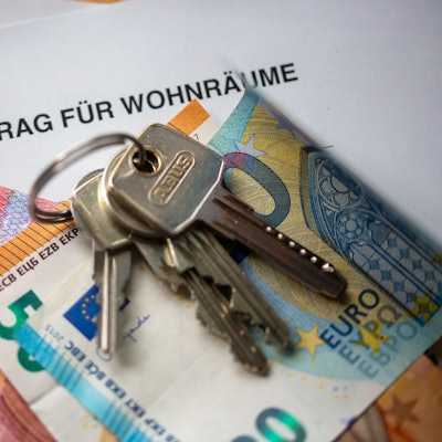 Ein Mietvertrag für Wohnräume liegt zusammen mit Geldscheinen und Wohnungsschlüsseln auf einem Tisch.