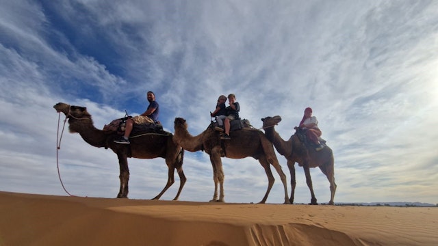 Eine Familie bei einer Kameltour in der Wüste.
