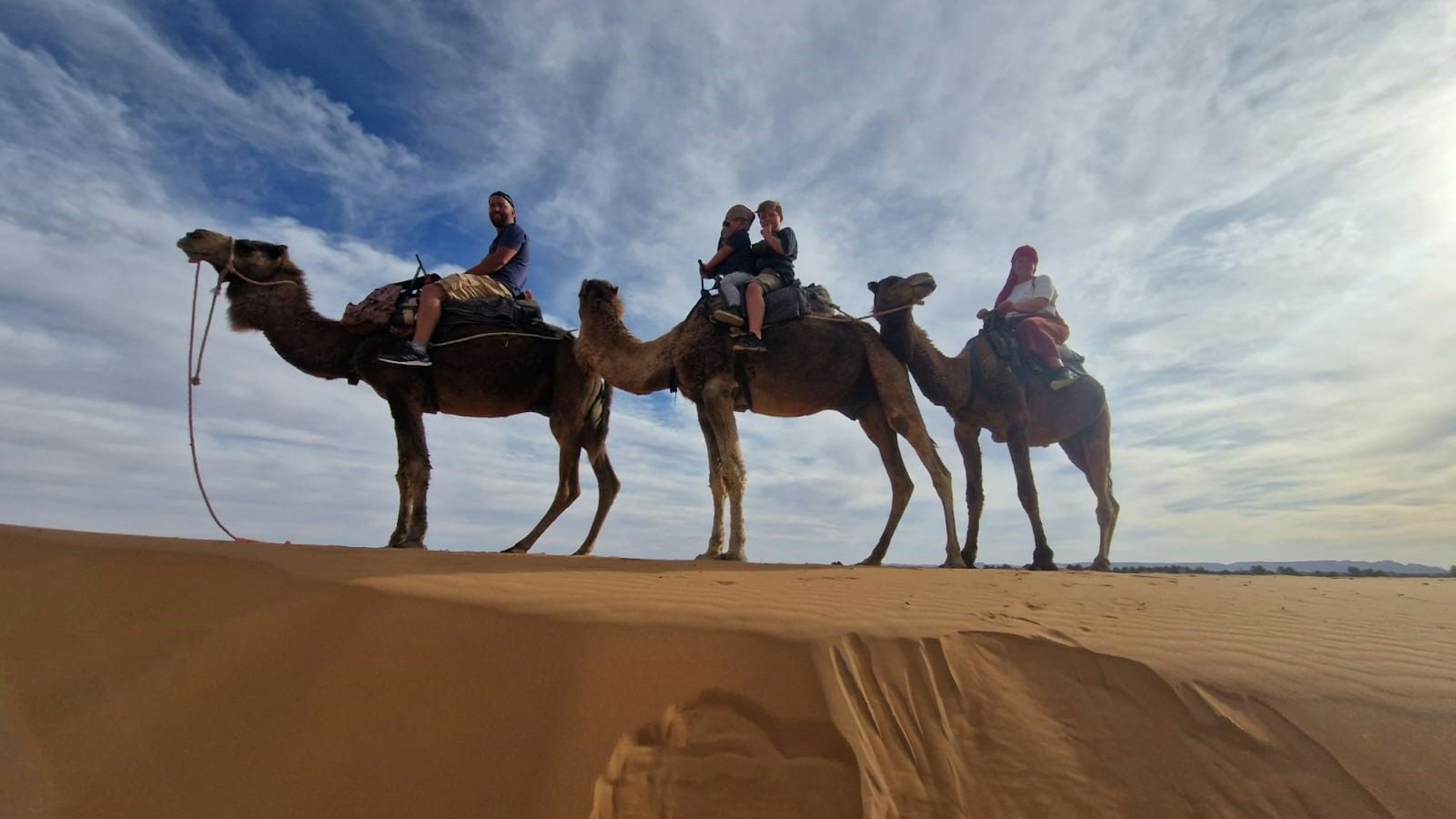 Eine Familie bei einer Kameltour in der Wüste.