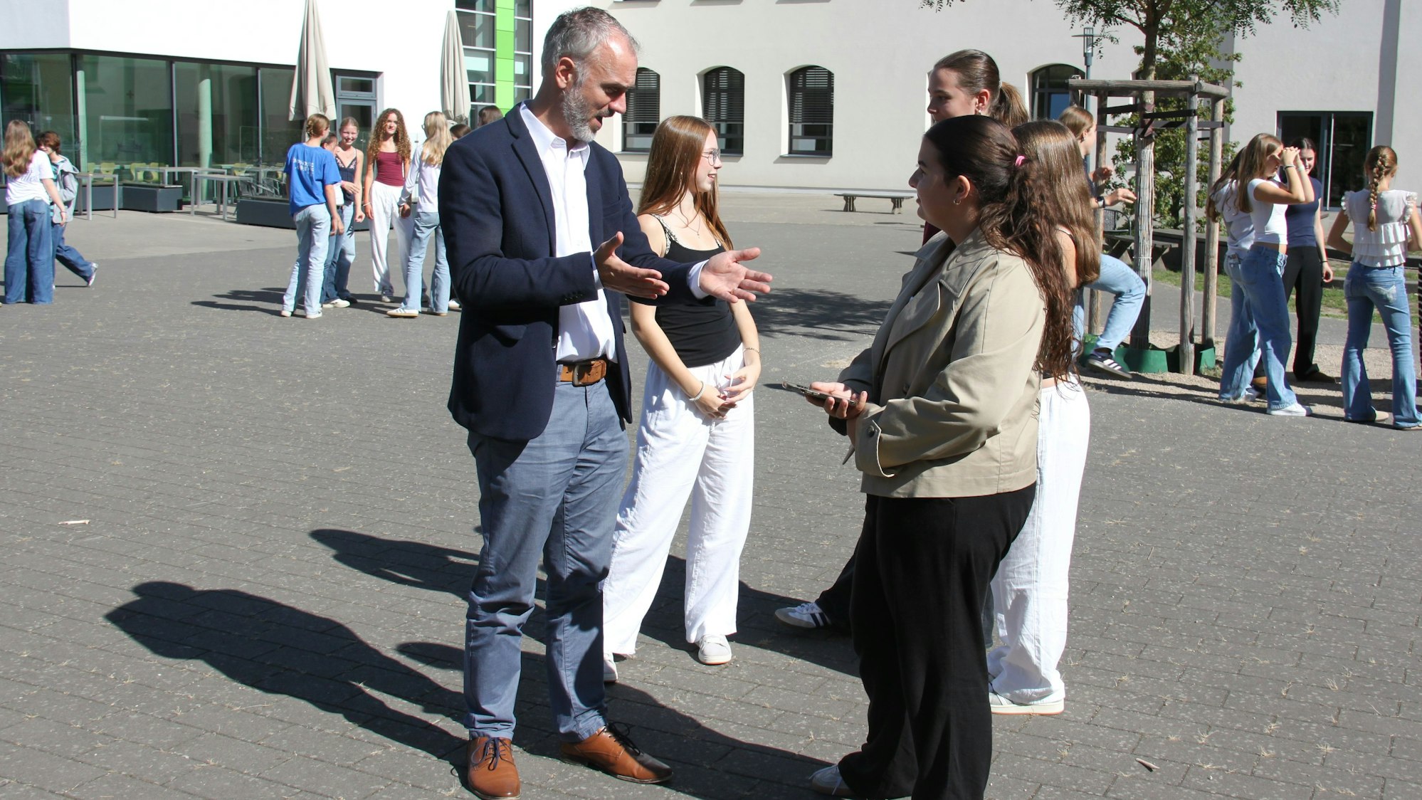 Schulleiter Dr. Carsten Oerder spricht mit einer Gruppe Schülerinnen über das Handyverbot auf dem Schulhof.