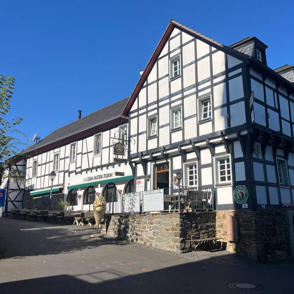 Die Gaststätte „Zum Alten Turm“ in Hennef-Stadt Blankenberg steht direkt gegenüber des Katharinenturms, dessen Schatten auf das Fachwerkhaus fällt.
