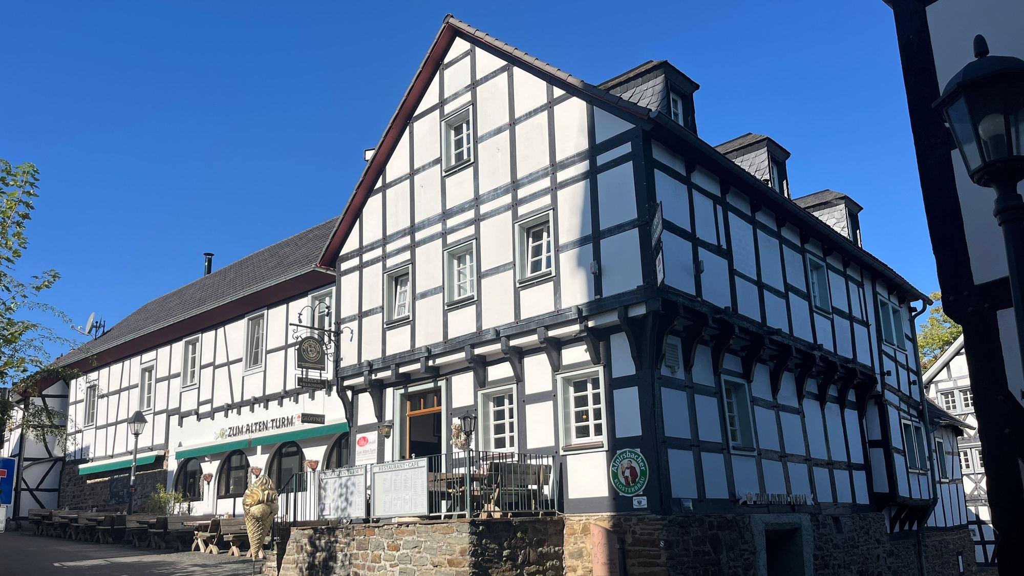 Die Gaststätte „Zum Alten Turm“ in Hennef-Stadt Blankenberg steht direkt gegenüber des Katharinenturms, dessen Schatten auf das Fachwerkhaus fällt.