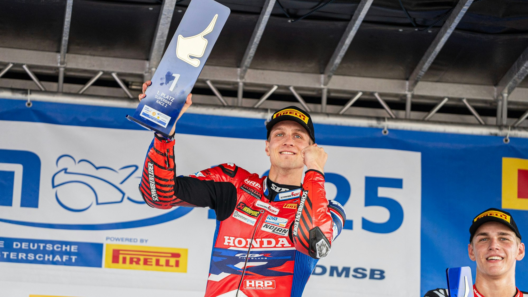 Florian Alt reckt auf dem Siegerpodest die Faust und den Siegerpokal.