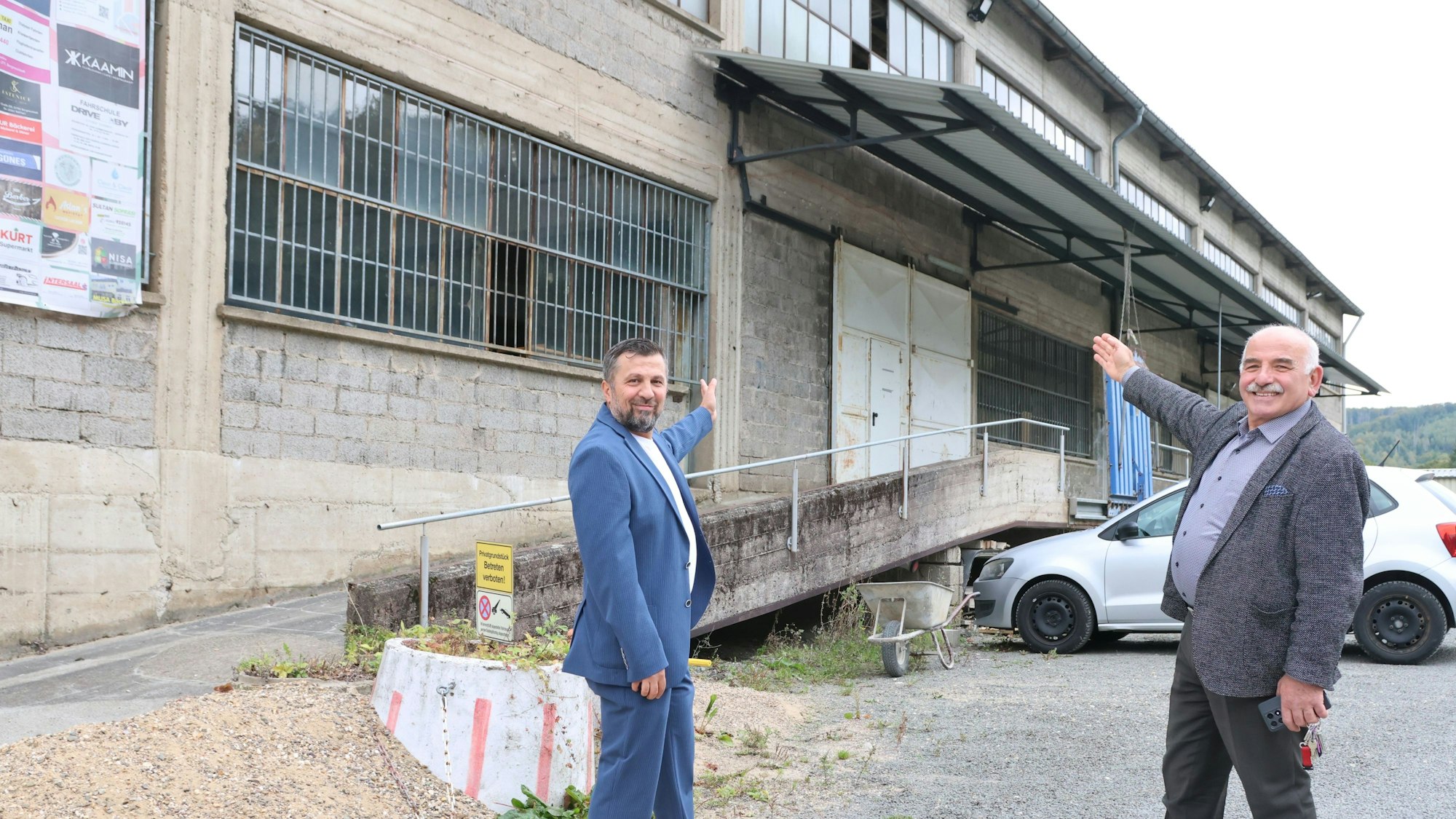 Zwei Männer zeigen auf ein altes Gebäude.