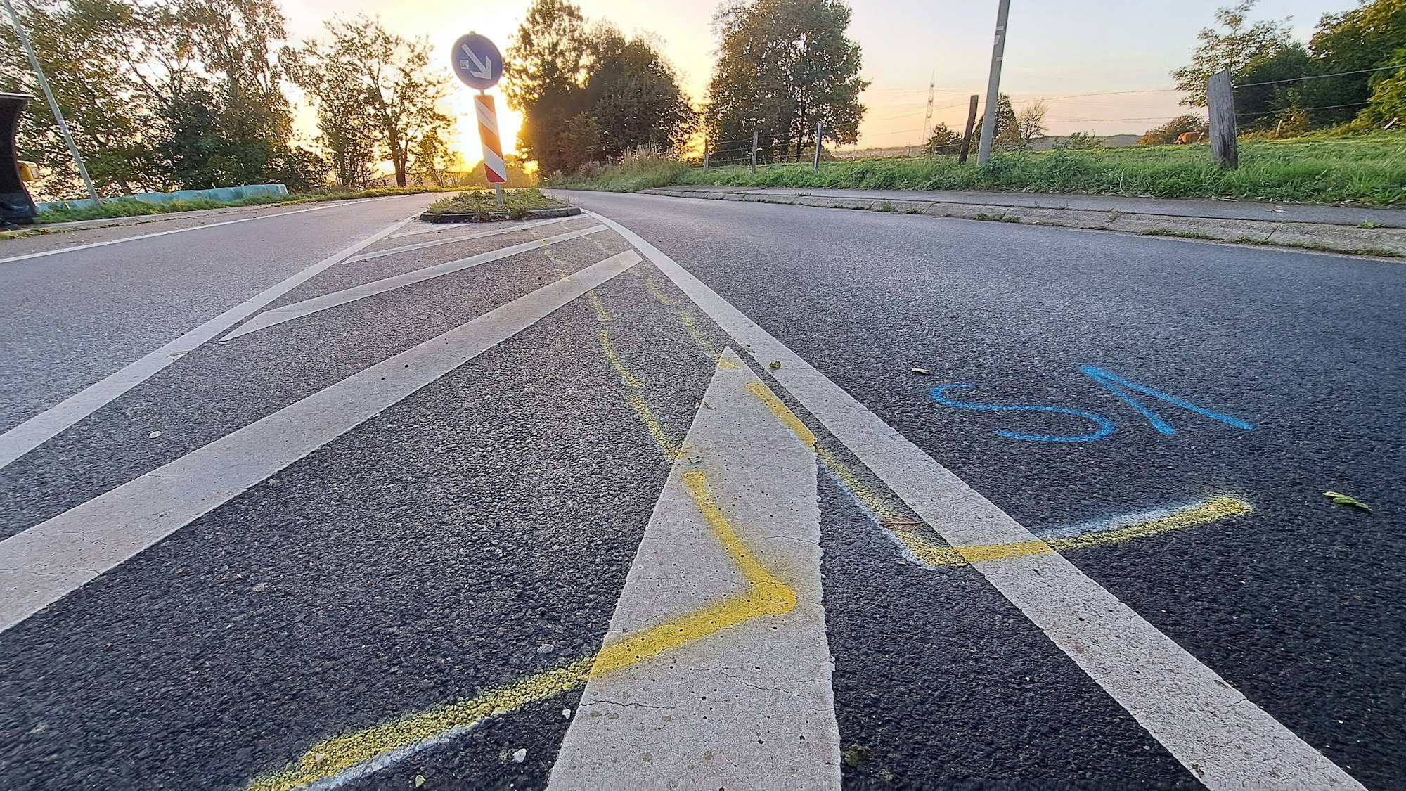 Unfallmarkierungen sind auf der Kreisstraße bei Rösrath-Stöcken vor einer Verkehrsinsel zu sehen.
