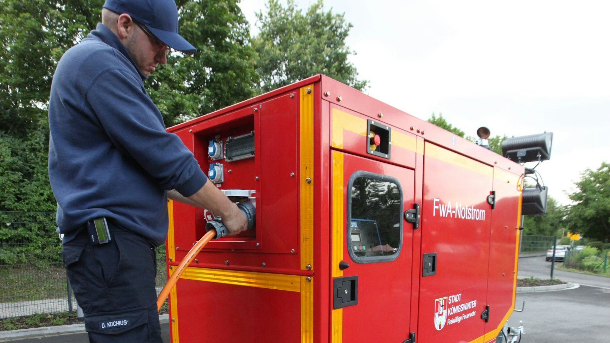 Ein Feuerwehrmann an einem roten Notstromaggregat.