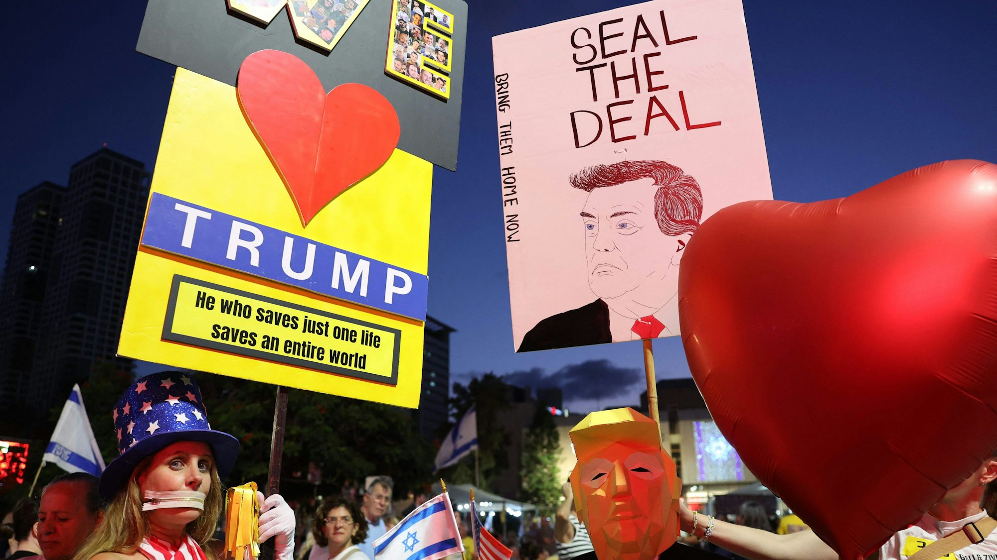 A man wearing a mask in effigy of US President Donald Trump, holds a heart-shaped balloon during a rally organised by families of hostages held in the Gaza Strip since October 2023, in the plaza outside the Tel Aviv Museum of Art, known as the "Hostages' Square", in Tel Aviv on October 4, 2025.