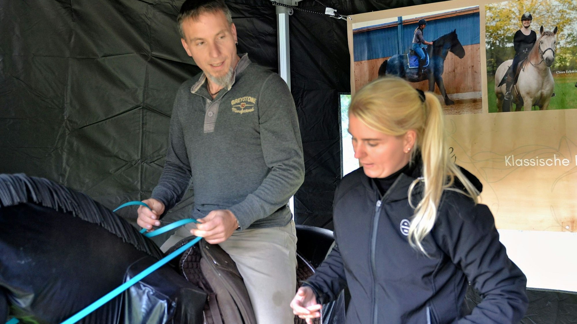 Das Bild zeigt Markus Kremer, der auf einem Reitsimulator sitzt. Die Trainerin steht daneben.