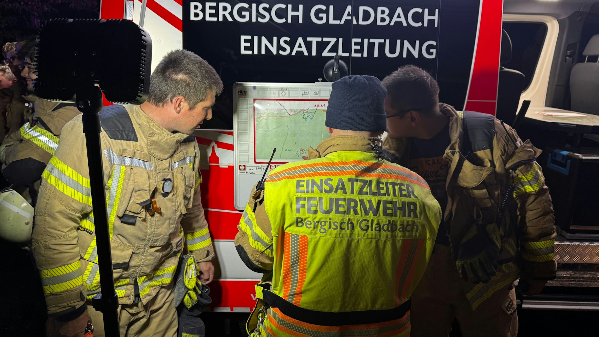 Die Einsatzkräfte der Feuerwehr Bergisch Gladbach bei der Suche nach der vermissten Person im Königsforst am Einsatzleitfahrzeug.