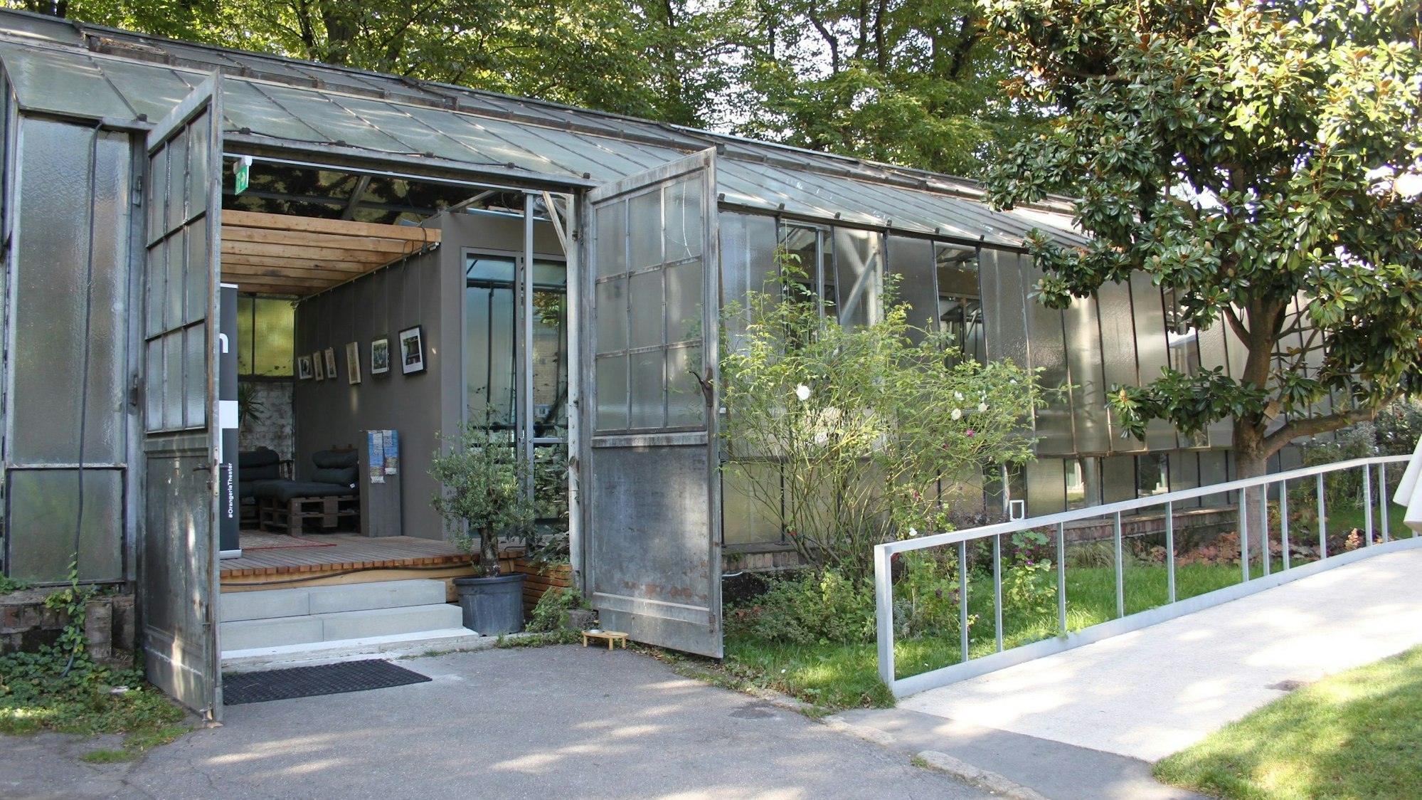 Ein Gewächshaus hat seine Türen geöffnet, eine Rampe führt zum Eingang.