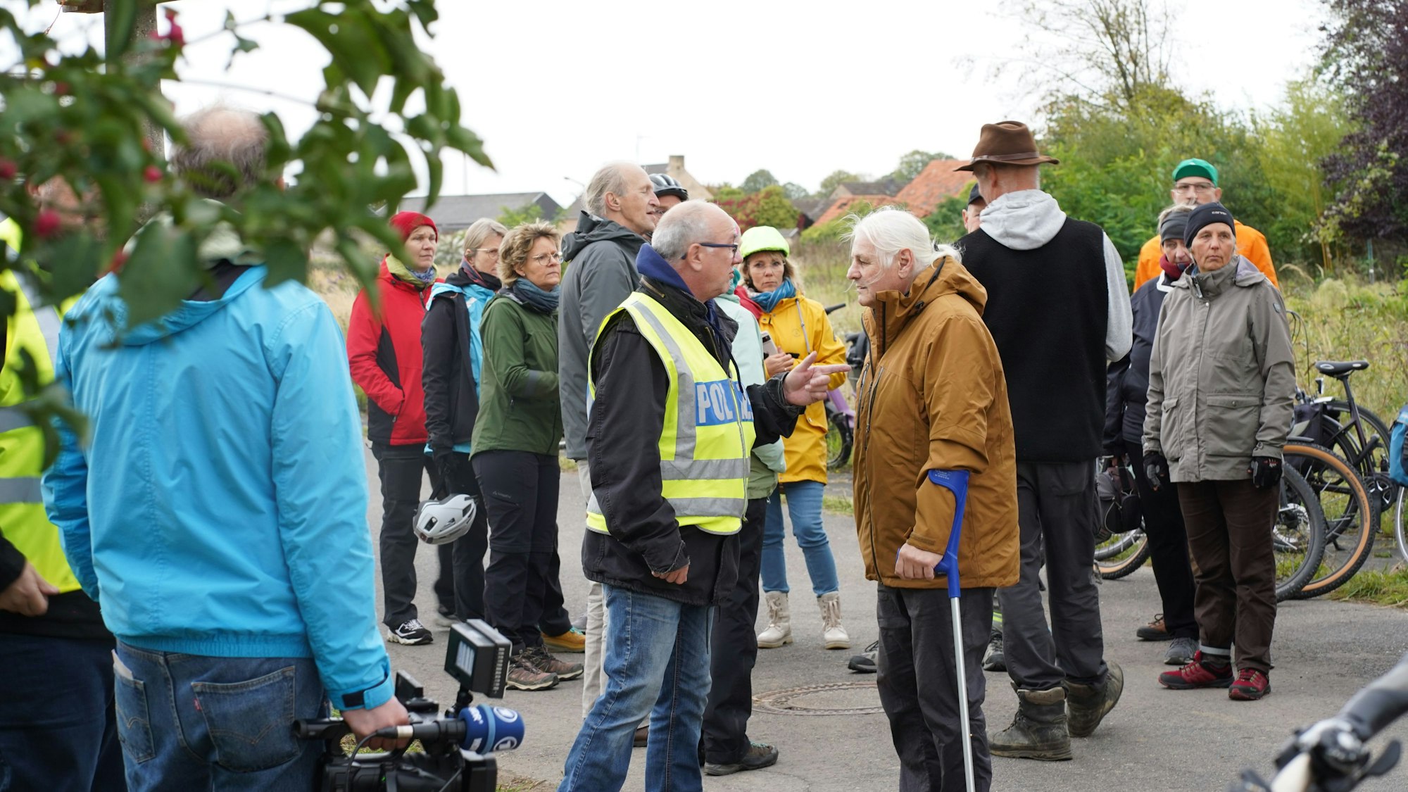 Das Foto zeigt eine Menschengruppe, davon einer Polizist.