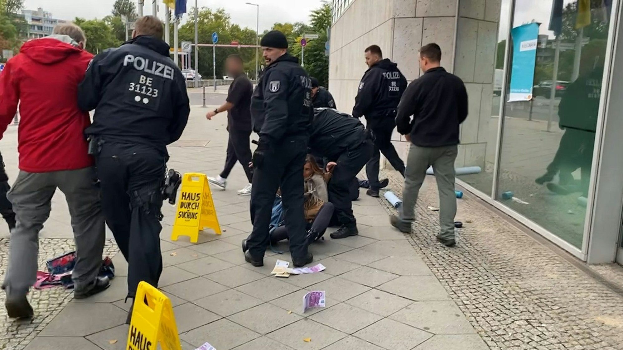Polizisten versuchen eine Person, die am Boden vor der CDU-Bundeszentrale sitzt, zu entfernen. Links wird eine weitere Person von der Polizei weggeführt.