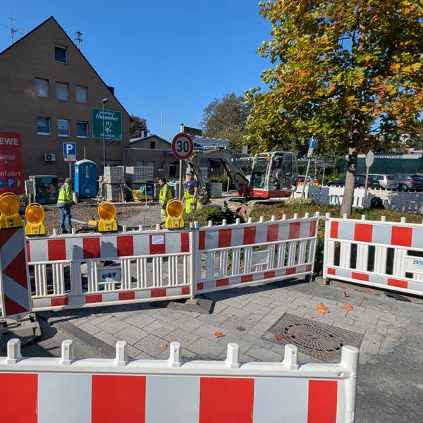 Das Foto zeigt die Bauarbeiten mit einem Bagger hinter Bauzäunen.