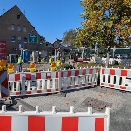 Das Foto zeigt die Bauarbeiten mit einem Bagger hinter Bauzäunen.