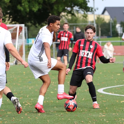 Ein Fußballer des SV Weiden tritt auf den Ball, der Gegenspieler der JSG Erft schaut auf den Ball.