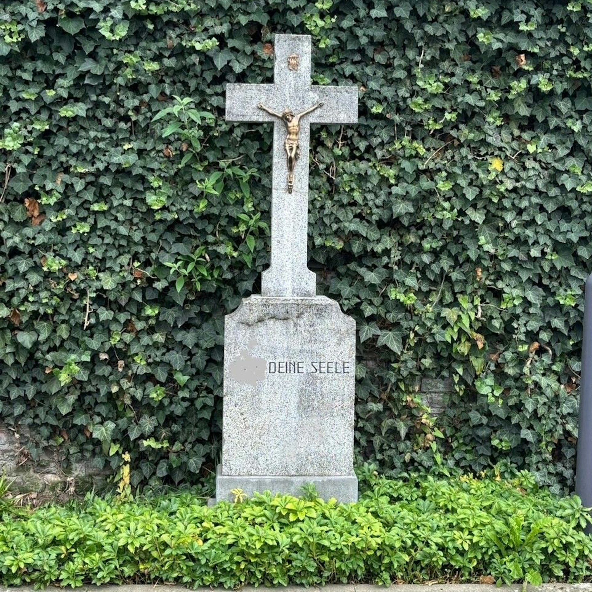 Auf dem Bild ist ein altes Steinkreuz mit einer Inschrift zu sehen.