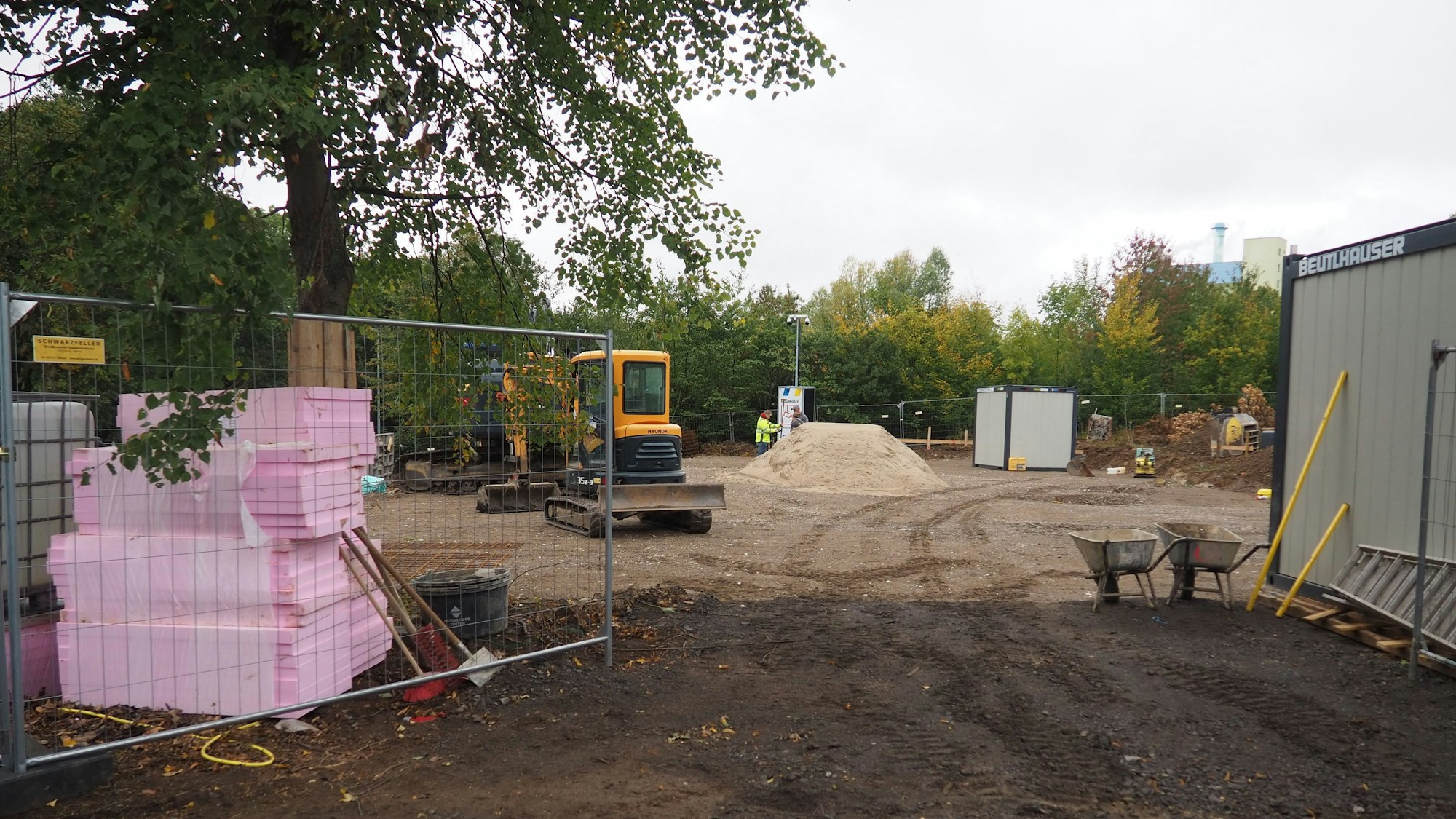 Das Bild zeigt einen Blick auf die Baustelle. Links ist Material gelagert, rechts steht ein Container.