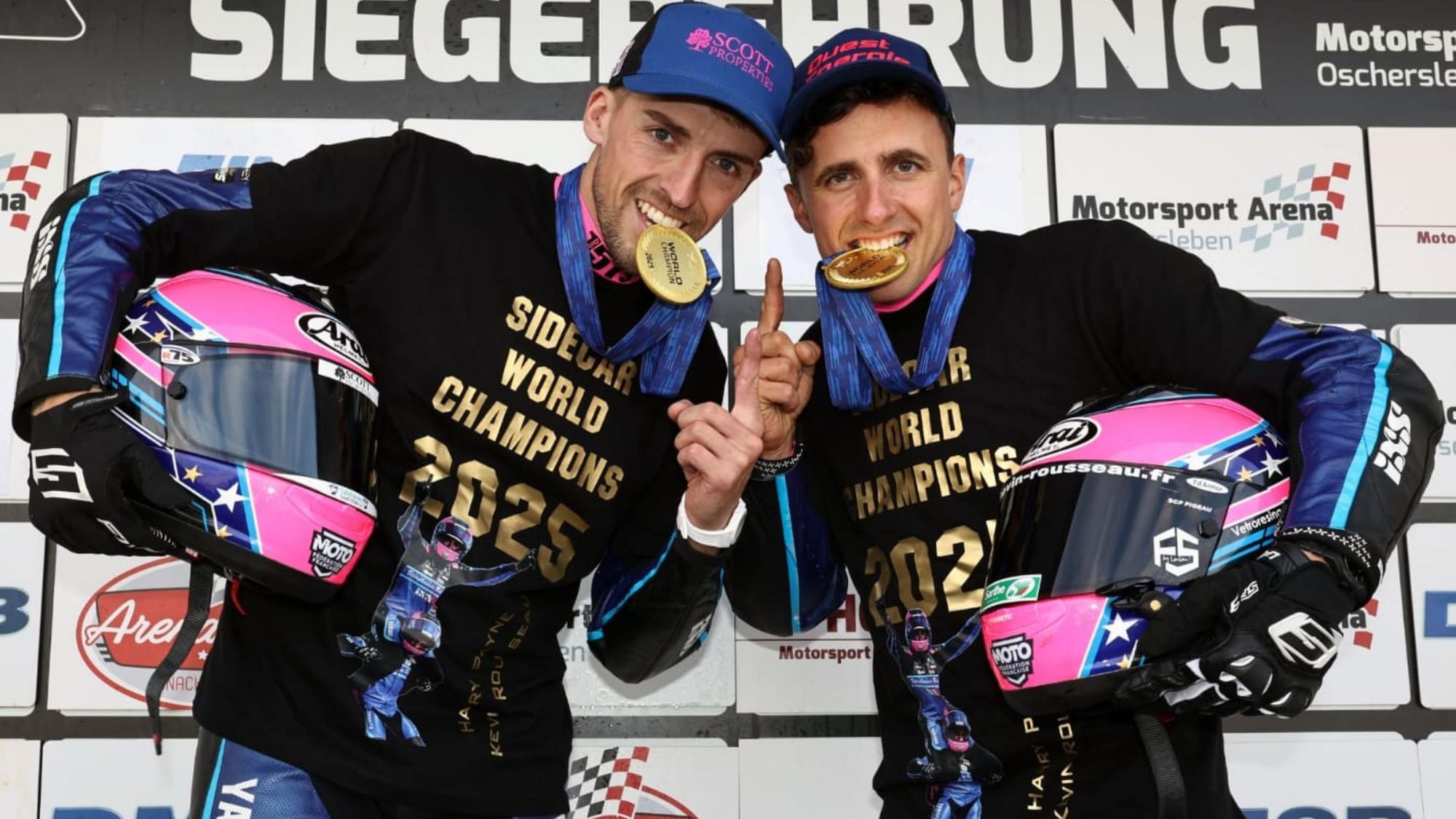 Zu sehen sind zwei Motorsportler, die auf Goldmedaillen beißen.