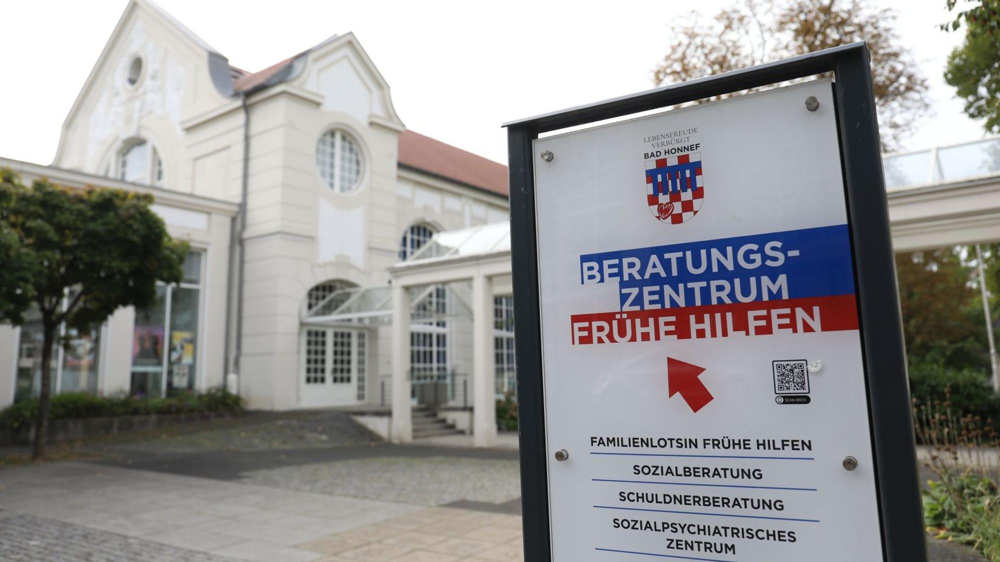 Ein Schild mit den Angeboten des Beratungszentrums Frühe Hilfe, im Hintergrund ein historisches Jugendstilgebäude.