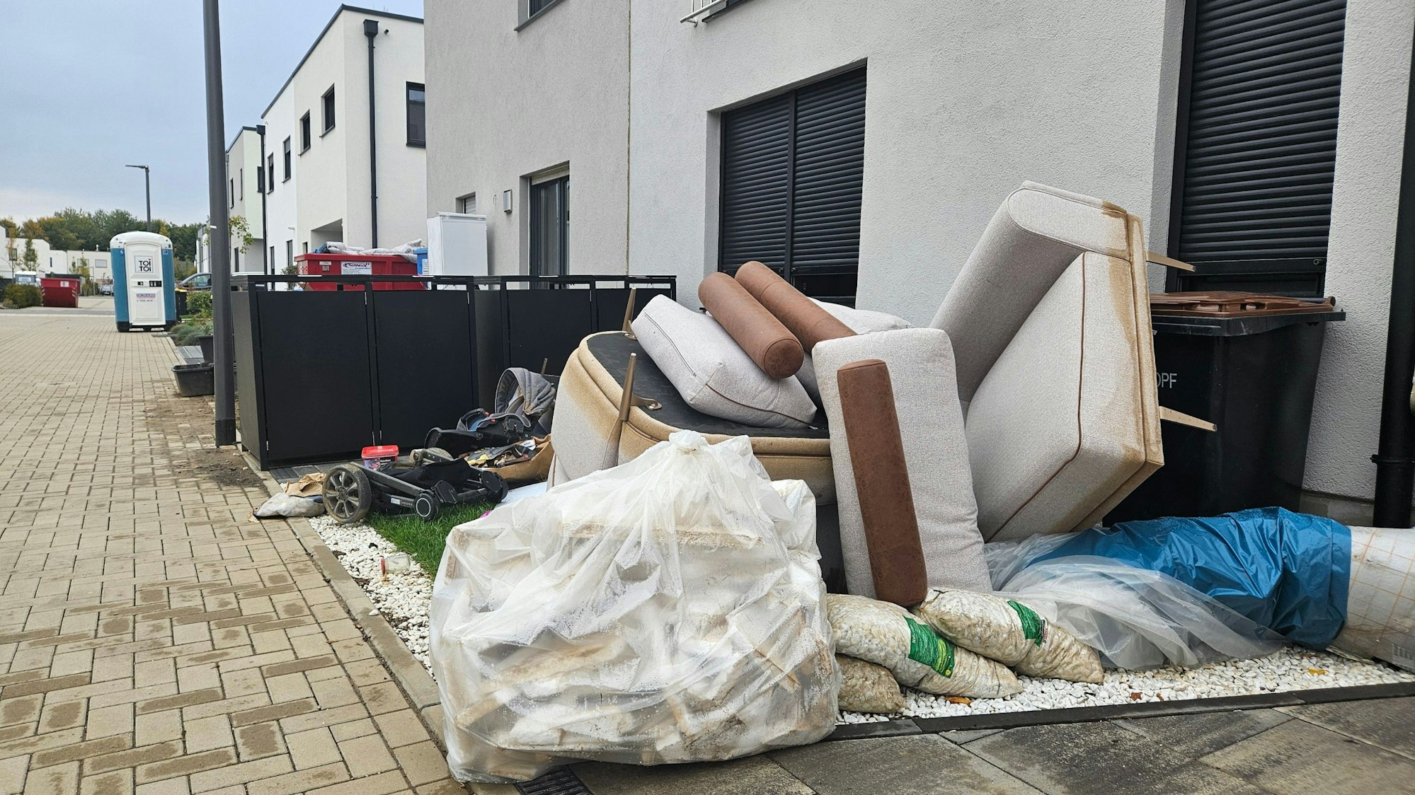 Zu sehen ist Sperrmüll vor einem Haus in einer Neubausiedlung.