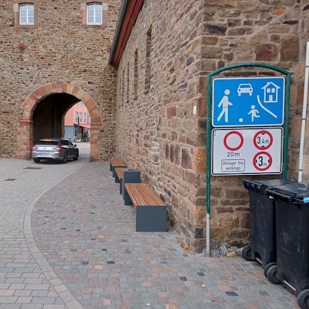 Ein Auto fährt durch das Orchheimer Tor in Bad Münstereifel, ein Fußgänger betritt den verkehrsberuhigten Bereich davor.