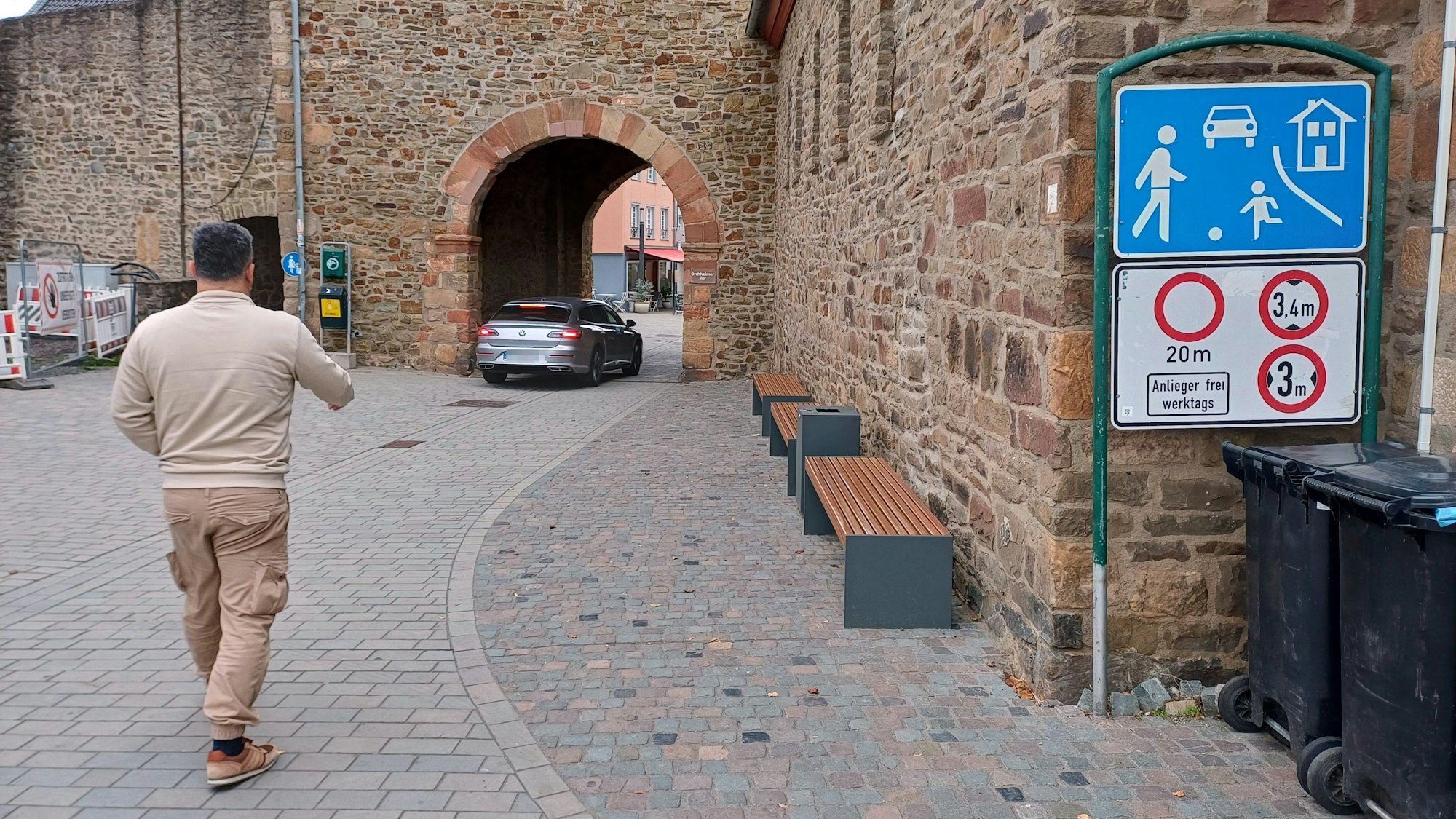Ein Auto fährt durch das Orchheimer Tor in Bad Münstereifel, ein Fußgänger betritt den verkehrsberuhigten Bereich davor.