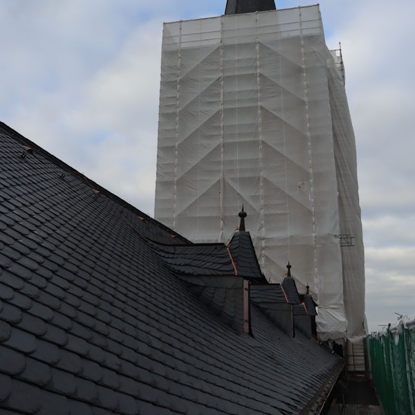 Zu sehen ist ein Kirchturm, der in ein Schutznetz gehüllt ist.